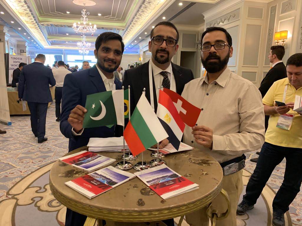 Dental professionals at an international dental congress, one holding the flag of Pakistan