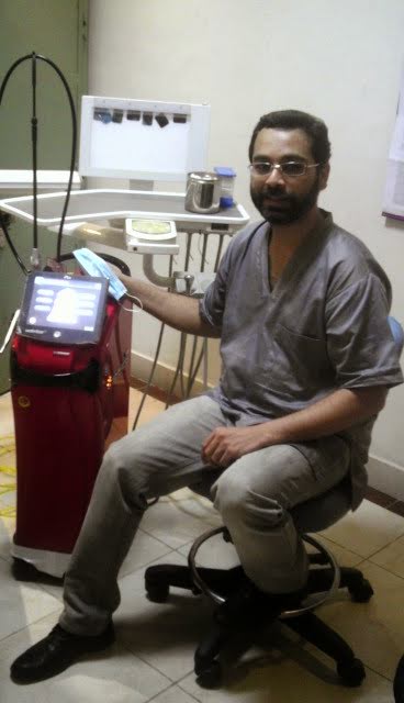Dr. Asim Habib Vohra seated beside a BioLase Waterlase dental laser in the treatment room