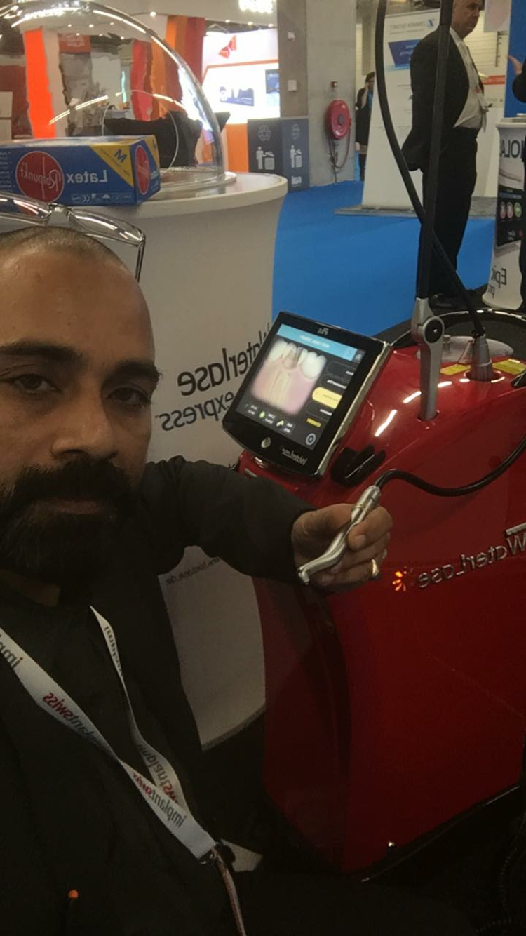 A dentist holding the handpiece of a Waterlase dental laser at an international dental exhibition
